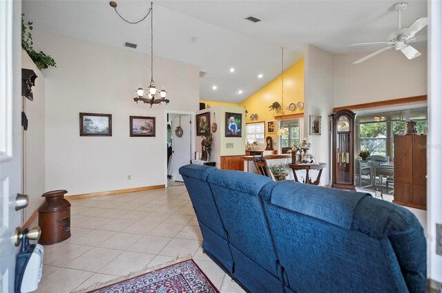 living room with light tile patterned floors, ceiling fan with notable chandelier, and high vaulted ceiling