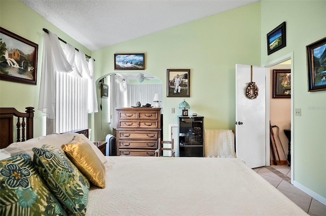 bedroom featuring lofted ceiling, wine cooler, a textured ceiling, and light tile patterned flooring