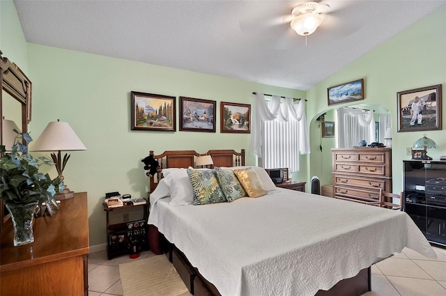 bedroom featuring ceiling fan, light tile patterned floors, a textured ceiling, and vaulted ceiling