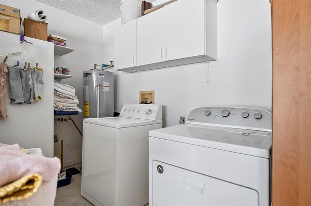 washroom with electric water heater, a textured ceiling, cabinets, and washing machine and dryer