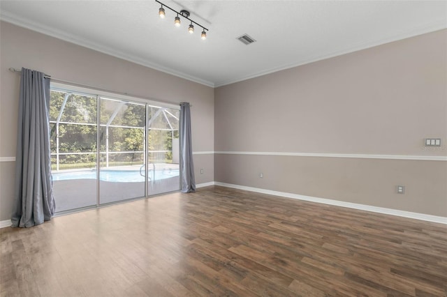 empty room with ornamental molding, track lighting, and dark hardwood / wood-style flooring