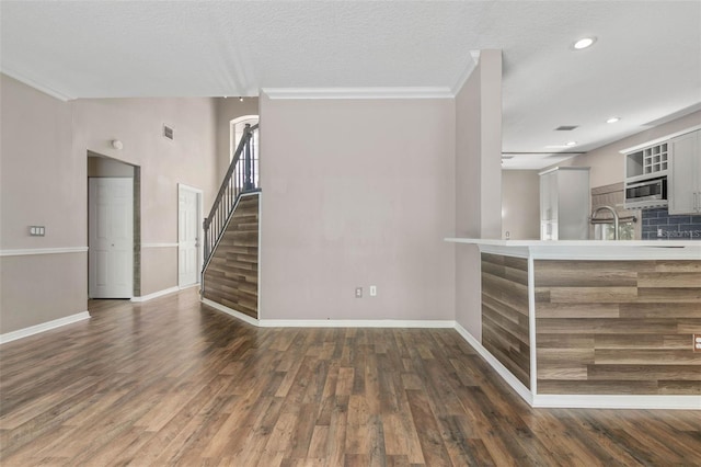 interior space with ornamental molding, a textured ceiling, and dark hardwood / wood-style floors