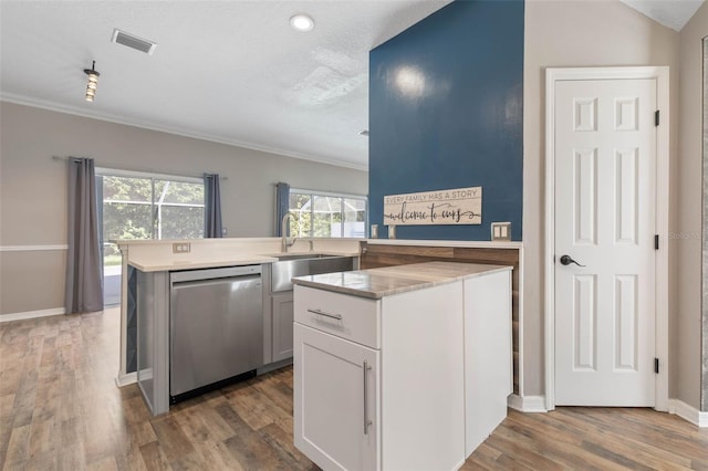 kitchen featuring dishwasher, kitchen peninsula, hardwood / wood-style floors, white cabinets, and a textured ceiling