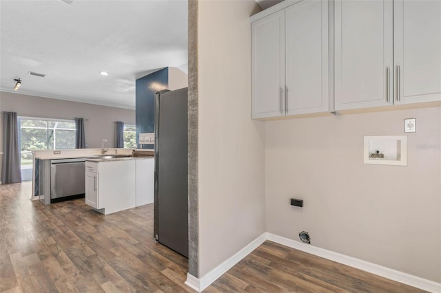 clothes washing area featuring electric dryer hookup, washer hookup, sink, crown molding, and dark hardwood / wood-style flooring