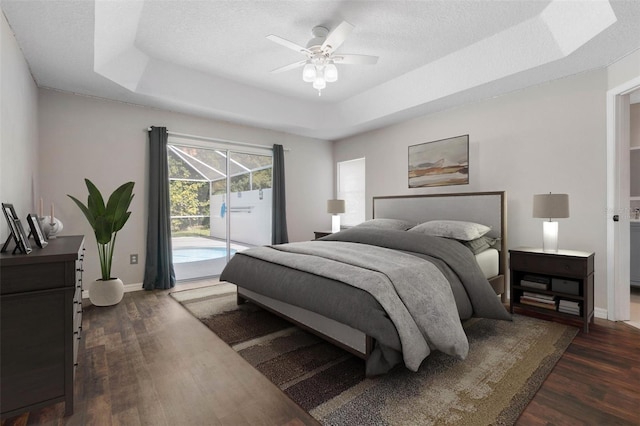 bedroom featuring ceiling fan, a raised ceiling, access to outside, and dark hardwood / wood-style flooring