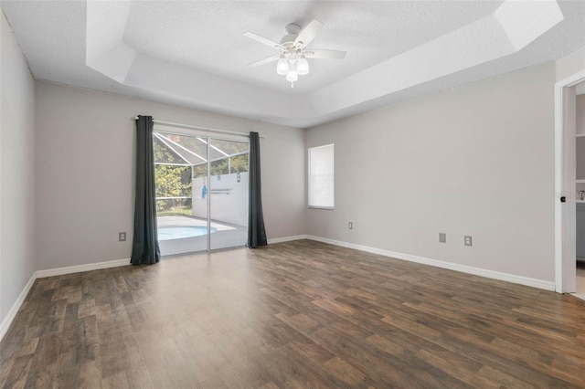 spare room featuring dark wood-type flooring, a tray ceiling, a textured ceiling, and ceiling fan