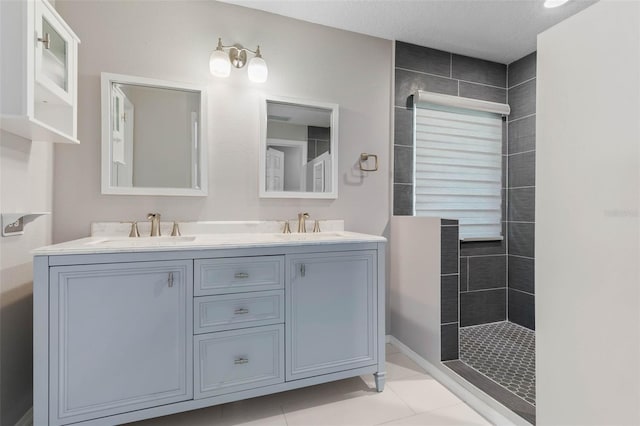 bathroom with vanity, a textured ceiling, tile patterned flooring, and tiled shower