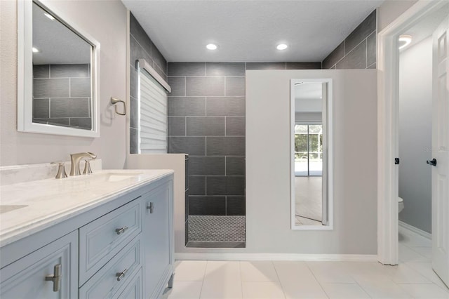 bathroom with tiled shower, tile patterned floors, toilet, vanity, and a textured ceiling