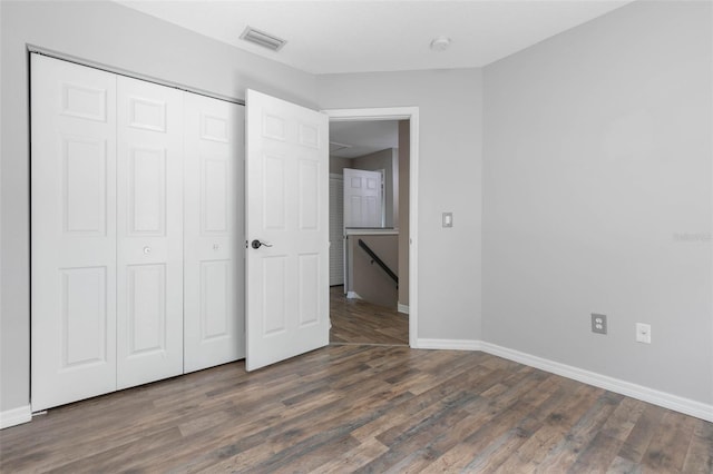 unfurnished bedroom with a closet and dark hardwood / wood-style flooring