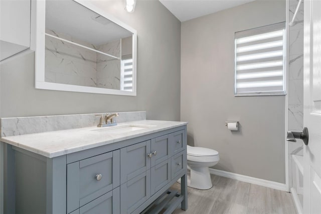 bathroom featuring vanity, hardwood / wood-style floors, a tile shower, and toilet