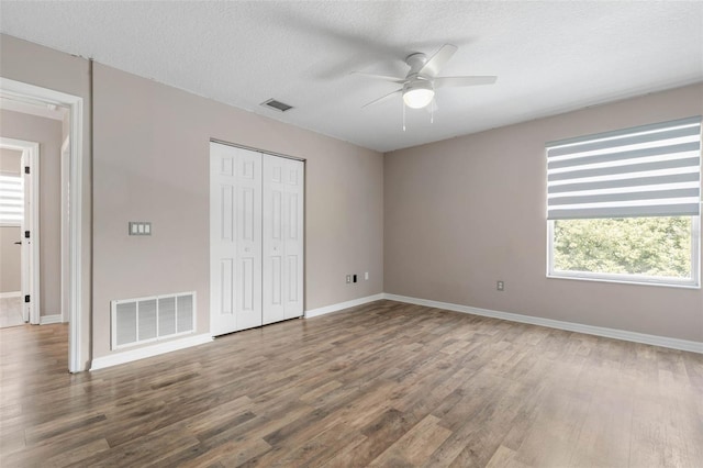 unfurnished bedroom featuring a textured ceiling, wood-type flooring, a closet, and ceiling fan