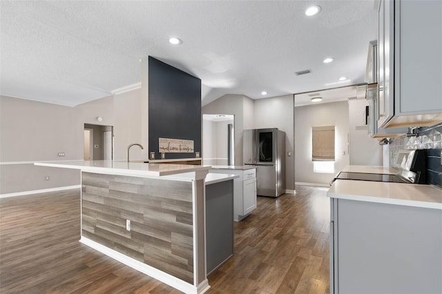 kitchen featuring black range, a kitchen island with sink, a textured ceiling, and dark hardwood / wood-style flooring