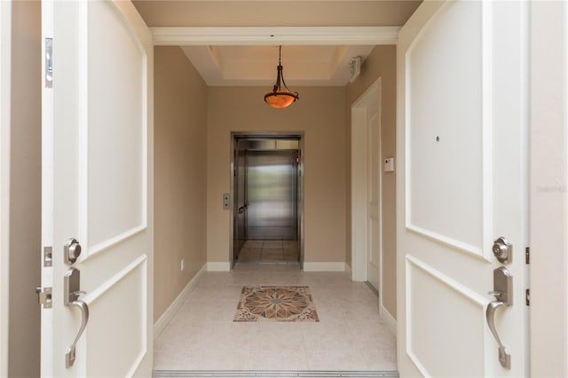 hallway with a raised ceiling, elevator, and light tile patterned floors