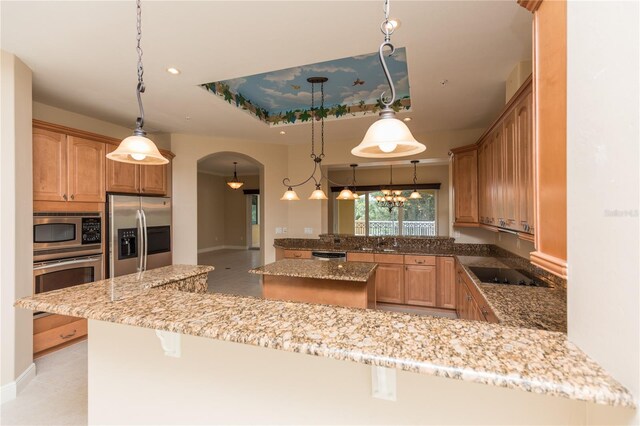 kitchen featuring a breakfast bar, light stone counters, kitchen peninsula, hanging light fixtures, and stainless steel appliances