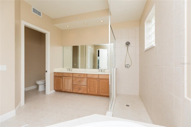 bathroom featuring a tile shower, tile patterned flooring, vanity, and toilet