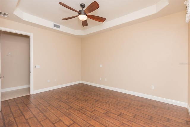 empty room featuring ceiling fan, a tray ceiling, and hardwood / wood-style floors