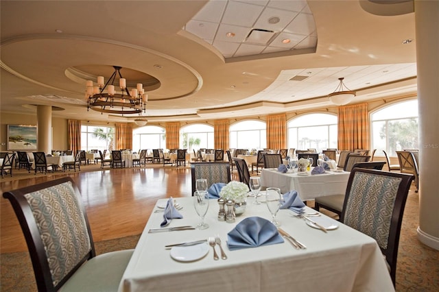 dining area featuring wood-type flooring, a tray ceiling, and a chandelier