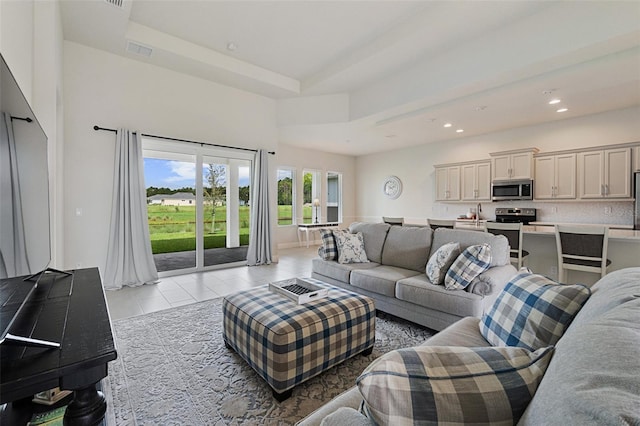 living room featuring a tray ceiling and light tile patterned floors