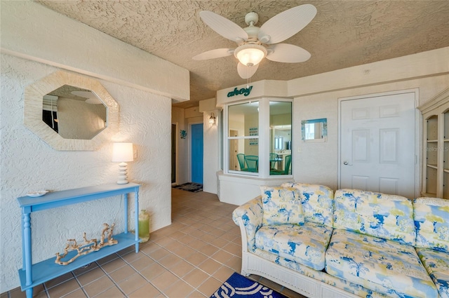 living room featuring ceiling fan, a textured ceiling, and tile patterned floors