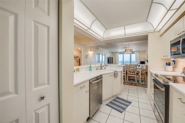 kitchen with sink, light tile patterned floors, decorative light fixtures, white cabinetry, and stainless steel appliances