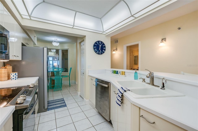 kitchen featuring stainless steel appliances, white cabinets, light tile patterned floors, and sink