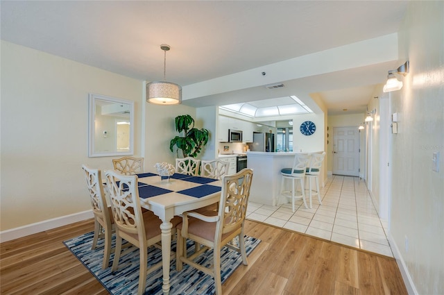 dining room with light hardwood / wood-style floors and a skylight