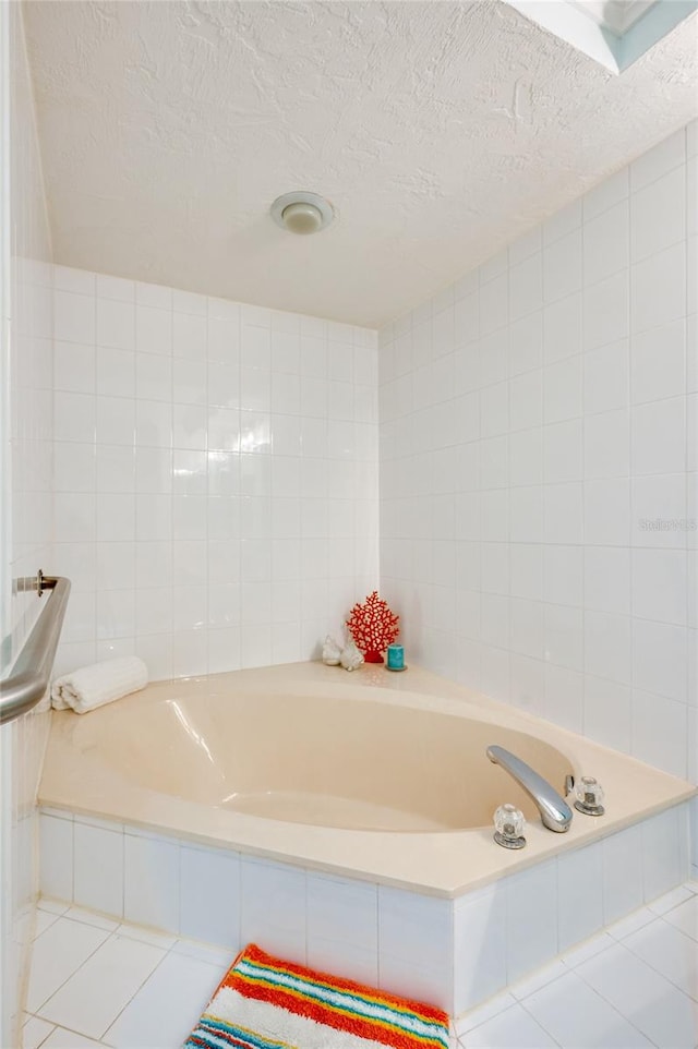 bathroom with tiled tub, a textured ceiling, tile walls, and tile patterned floors