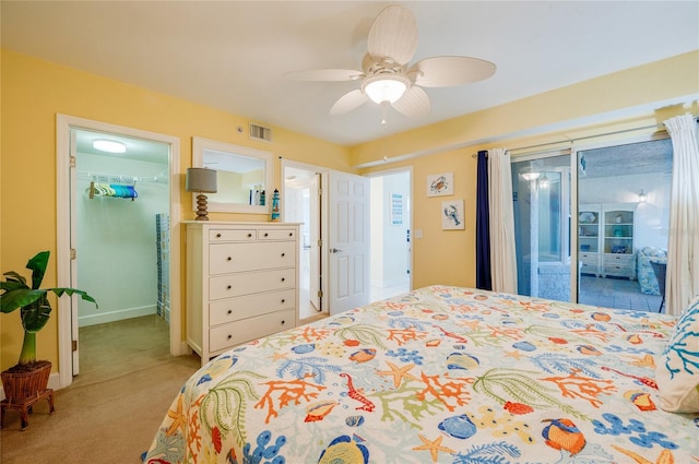 carpeted bedroom featuring access to outside, ceiling fan, and a walk in closet