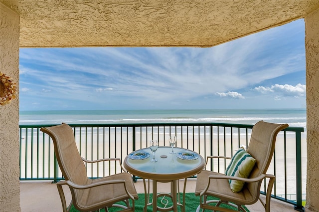 balcony with a water view and a view of the beach