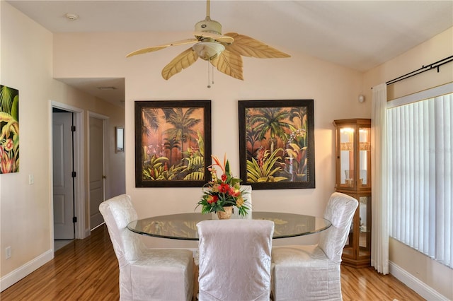 dining room with ceiling fan, vaulted ceiling, and light hardwood / wood-style flooring