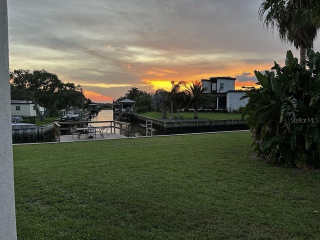 yard at dusk with a water view and a dock