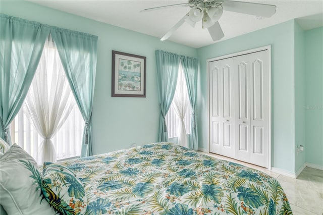 bedroom with multiple windows, light tile patterned flooring, ceiling fan, and a closet