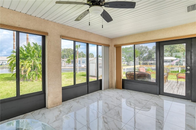 sunroom featuring ceiling fan and a water view