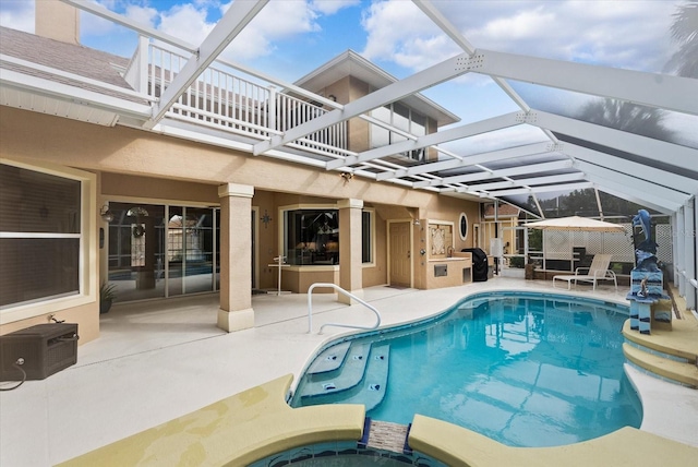 outdoor pool featuring a patio area, glass enclosure, an in ground hot tub, and a wall unit AC