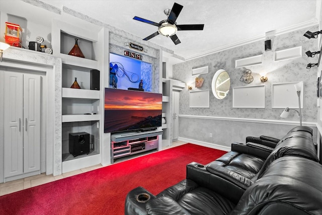 living room featuring built in shelves, ceiling fan, ornamental molding, and wallpapered walls