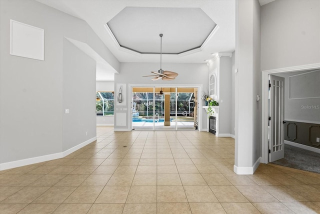 entrance foyer with light tile patterned floors, a ceiling fan, baseboards, a high ceiling, and a raised ceiling