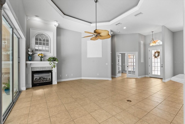 unfurnished living room featuring visible vents, baseboards, a tray ceiling, and a glass covered fireplace