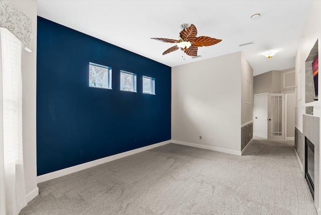 interior space with a glass covered fireplace, ceiling fan, and baseboards