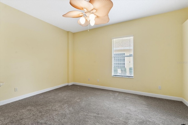 carpeted spare room featuring baseboards and ceiling fan