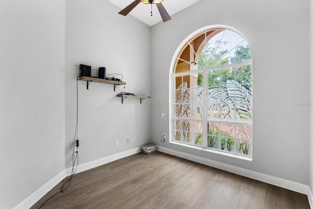 empty room with a wealth of natural light, baseboards, a ceiling fan, and wood finished floors