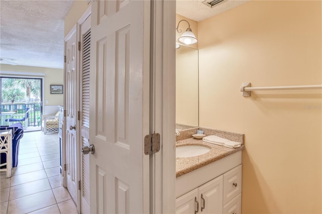 bathroom with tile patterned flooring, vanity, and a textured ceiling