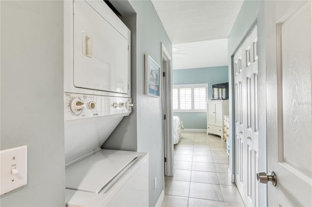 laundry room featuring light tile patterned flooring and stacked washer / drying machine