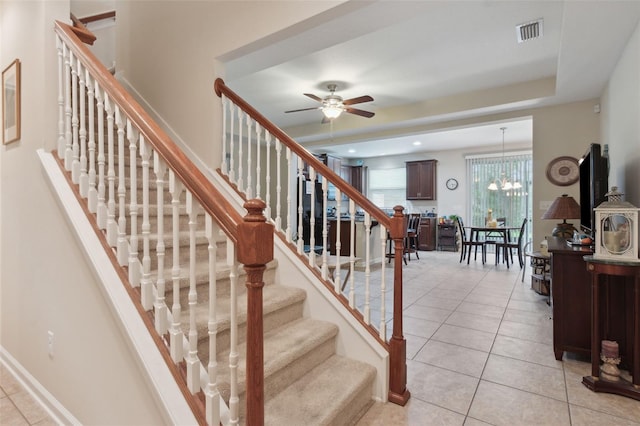 stairs featuring tile patterned flooring and ceiling fan with notable chandelier