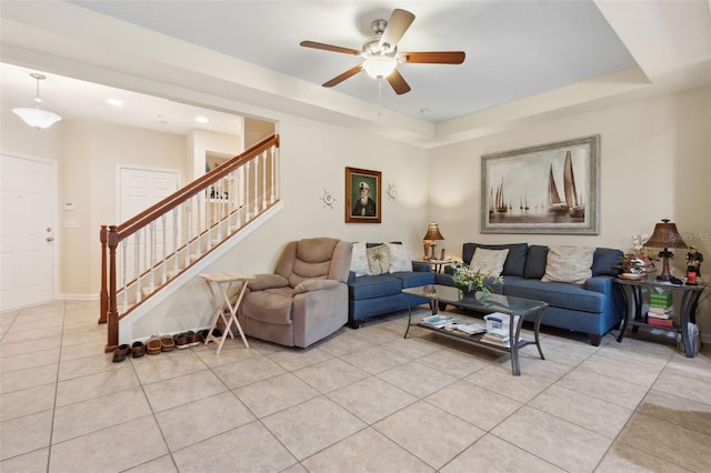 tiled living room with a tray ceiling and ceiling fan