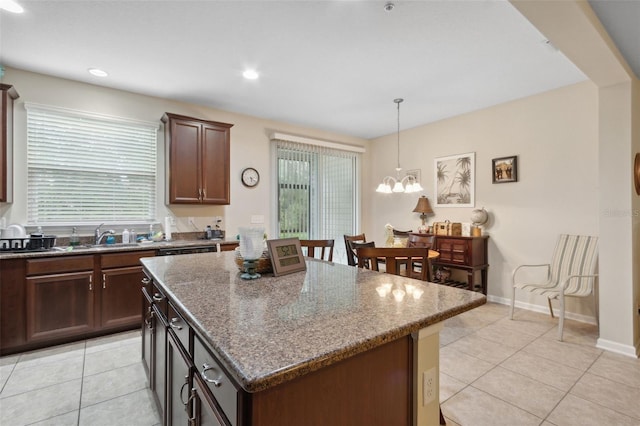 kitchen with dark stone counters, pendant lighting, a chandelier, light tile patterned floors, and a center island