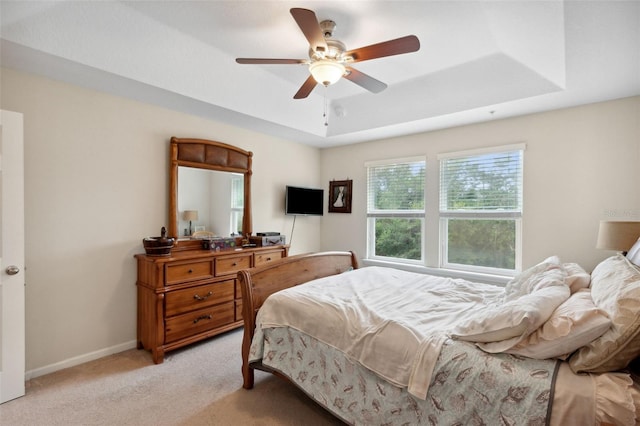 carpeted bedroom featuring a tray ceiling and ceiling fan