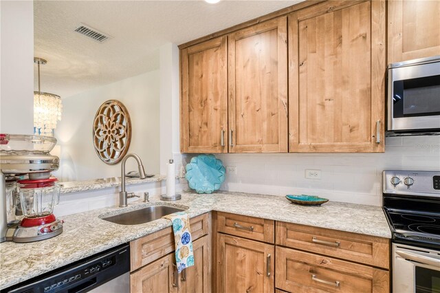 kitchen featuring appliances with stainless steel finishes, sink, and light stone countertops