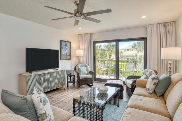 living room with light wood-type flooring, a textured ceiling, a wealth of natural light, and ceiling fan