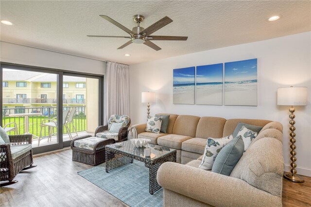 living room with a textured ceiling, ceiling fan, and wood-type flooring