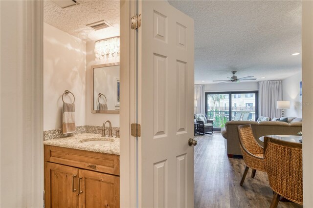 bathroom with a textured ceiling, vanity, ceiling fan, and hardwood / wood-style flooring